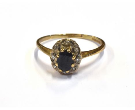 MODERN SAPPHIRE &amp; DIAMOND CLUSTER RING A 10.5 x 8.0mm claw and grain set oval cluster, featuring a 6 x 4mm oval dark blue