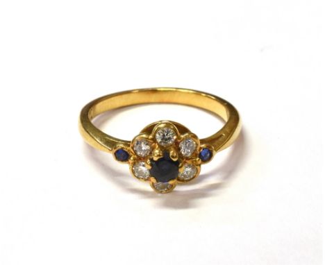 DIAMOND &amp; SAPPHIRE FLORAL CLUSTER RING A 3.2mm round mixed cut blue sapphire surrounded by five round brilliant cut diamo