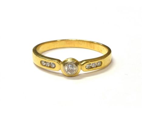 MODERN DIAMOND 18CT GOLD DRESS RING Bezel set round brilliant cut diamond, estimated 0.17 carats, flanked by channel set shou