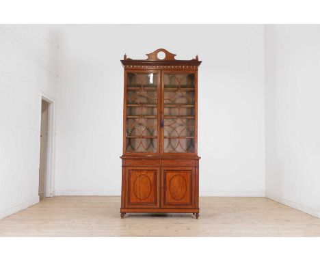 An Edwardian strung and crossbanded satinwood bookcase, c.1900, the top section with a convex mirrored crest, over turned pen