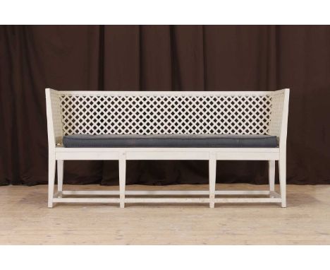 A painted wooden bench in the Georgian style, of recent manufacture, the high back, sides, and seat with lattice detail, rais