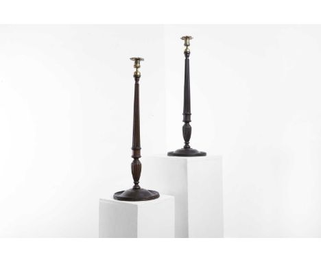 A matched pair of George IV-style mahogany library candlesticks, 19th century, each brass sconce over a reeded column on a ci