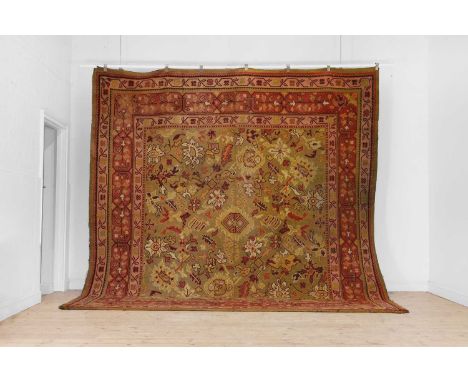 A Donegal Oushak wool carpet, early 20th century, woven with geometric floral motifs to a red and brown ground,345 x 325cmCon