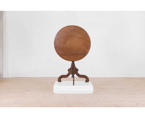 An oak tripod table, second half of the 18th century, the circular snap top raised on a turned baluster column and three scro