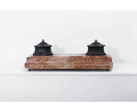 A rouge marble and patinated bronze desk stand, 19th century, fitted with two octagonal inkwells and covers, raised on a step