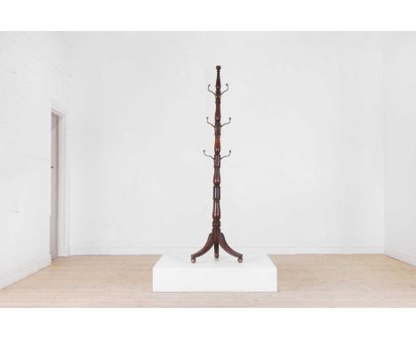 A Victorian mahogany hatstand, c.1840, with a turned baluster column issuing nine brass hooks, raised on tripod supports, ter