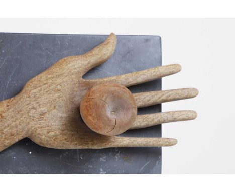 A carved fruitwood model, 20th century, in the form of an open palm holding an apple, initialled 'RB' to the slate base,23cm 