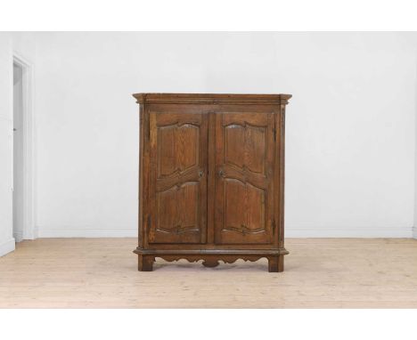 A small provincial oak cupboard, mid-18th century, North German, the canted rectangular top above a pair of panelled doors en