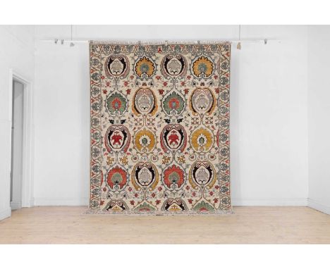 A Suzani-inspired wool carpet, of recent manufacture, woven with bold foliate motifs to a pale ground, 298 x 207cmCondition R