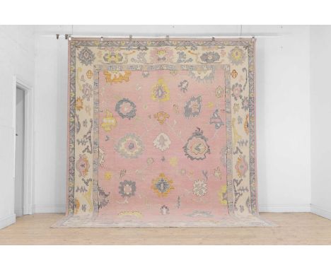 An Oushak wool carpet, of recent manufacture, woven with floral and foliate motifs to a pink ground, 372 x 280cmCondition Rep
