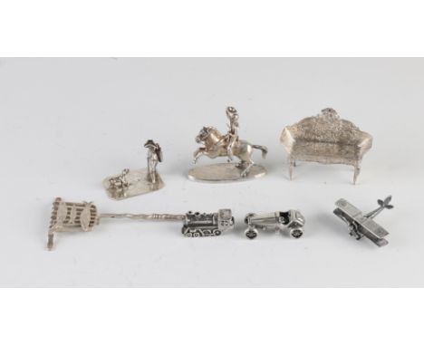 Lot with seven silver miniatures: a rider on a horse, an old airplane, a shovel with fish, a steam train, an old racing car, 