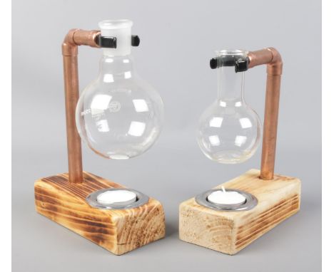 Two copper pipe and florence flask tea light holders mounted on wooden bases.  