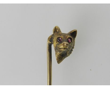 A yellow metal gentleman's tie pin in the form of a fox head with red stone cabochon eyes. 