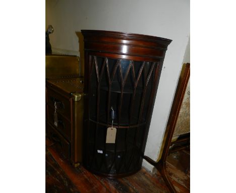 An Edwardian mahogany bow fronted hanging corner cabinet, having an astragal bar glazed door, enclosing three shelves. H.99cm