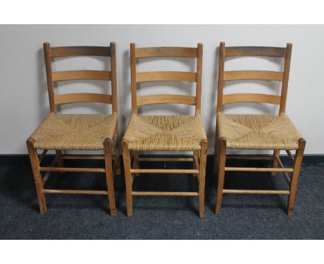 A set of three pine ladder back rush seated kitchen chairs 