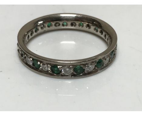 An 18ct white gold diamond and emerald full eternity ring, size N/O.