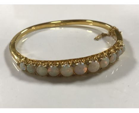 A fine 14ct gold graduated opal bangle, 21.2g, width internally approximately 60mm x 48 mm.