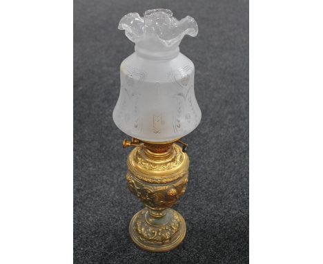 A continental brass embossed oil lamp with glass shade and chimney 