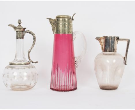 A ruby tinted glass claret jug with plated mounts, 28cm high and two others, both with plated mounts