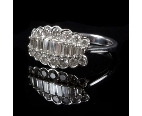 A diamond dress ring set with nine graduated baguette cut stones flanked by a row of graduated round mixed cut stones to eith