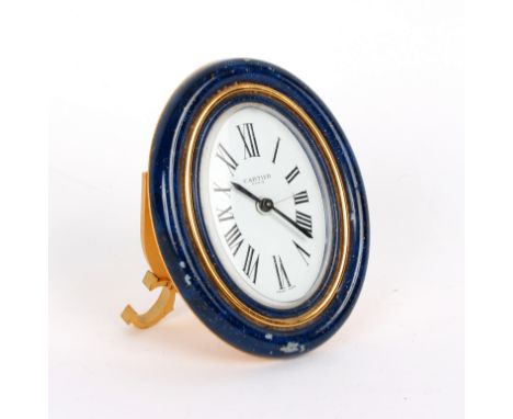 A Cartier alarm clock, the oval dial with Roman numerals signed Cartier Paris within a blue enamel frame on an easel support,