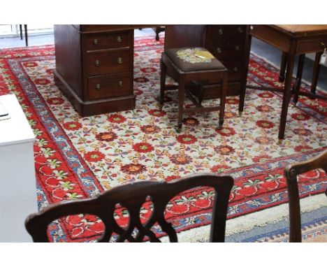 An Indian carpet, circa 1900, with ivory main field with flowerheads, red border with scallop trail with stylised foliate mot