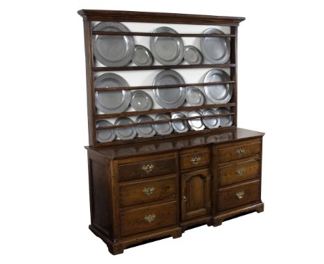 An 18th Century Derbyshire oak dresser with shelves over the breakfront base, fitted a cupboard and arrangement of seven draw