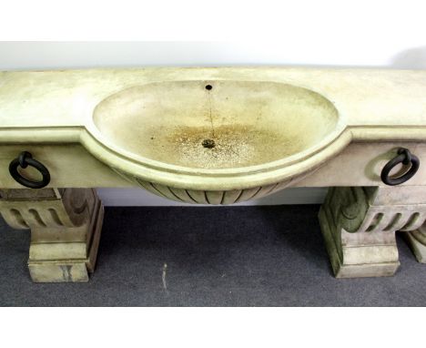 A reconstituted stone horse trough form sink, with large metal rings to the front, on end plinth supports, 171cm wide