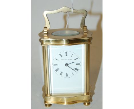 An early 20th century lacquered brass cased serpentine shaped carriage clock, having enamelled dial with Roman numerals, sign