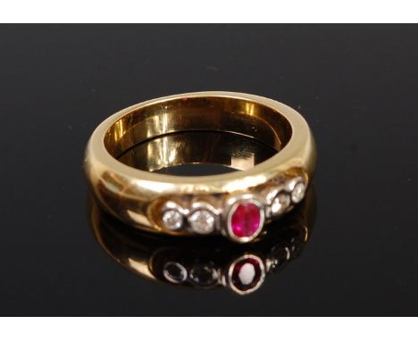 An 18ct gold, ruby and diamond ring, arranged as an illusion set oval cut ruby flanked to either side with a pair of graduate