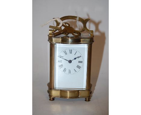 An early 20th century serpentine shaped lacquered brass cased carriage clock, having enamelled dial with Roman numerals and v