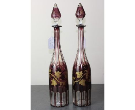 A pair of early 20th century Bohemian ruby flash cut decanters, of traditional form, with gilt vine decoration, star cut base
