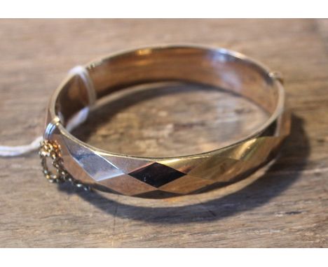 A 9ct. yellow gold hinged bangle, of faceted oval form, assayed Birmingham 1977. (19.7g)