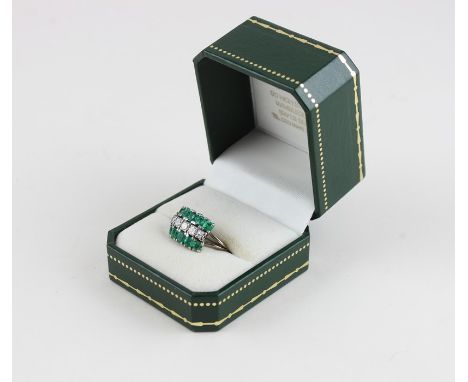 A white metal, diamond and emerald cluster ring,&nbsp;set row of five graduated round brilliant cut diamonds to centre, (tota