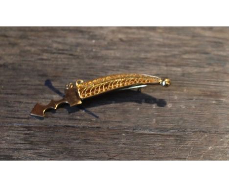An 18ct. yellow "Janbiya" gold brooch, having polished dagger fitting inside filigree work scabbard united by chain, stamped 