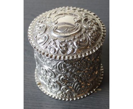 A late 19th century silver circular tea caddy, repousse embossed all over flower and 'C' scroll decoration, with pull-off dom