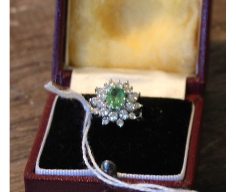 A white metal, green stone and diamond cluster ring, set oval mixed cut green stone to centre surrounded round brilliant cut 