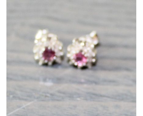 A pair of precious white metal diamond and ruby earrings, each set round cut ruby to centre surrounded ten single cut diamond