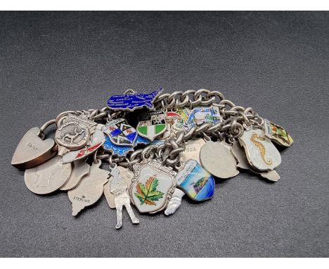A white metal charm bracelet, having approximately 30 attached white metal, enamel and other commemorative charms. 