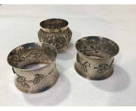 A pair of London silver hammered finish napkin rings, with stylised floral and leaf design in the Arts &amp; Crafts taste (h.