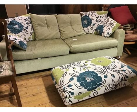 A modern three seater sofa upholstered in lime green plush fabric with squab and scatter floral cushions, with matching uphol