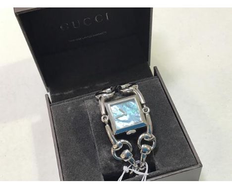A white metal Gucci lady's wristwatch with horsebit double strap and mother of pearl square dial with lozenge batons, complet