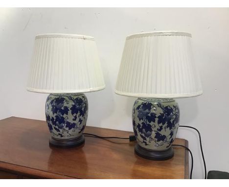 A pair of modern Chinese ginger jar style table lamps of ovoid form, with stylised peach design, complete with silk pleated s