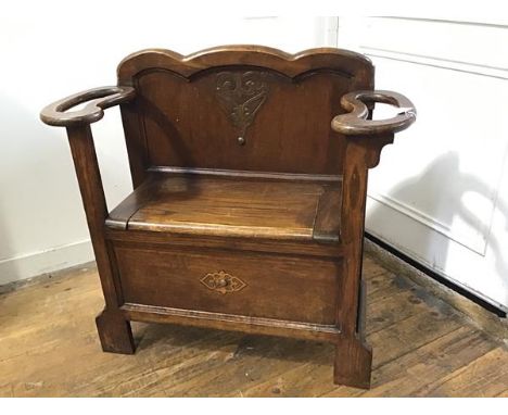 A 1920s/30s oak stick stand with panel shaped back, with lift up box seat and twin stick/umbrella stand rests to side, raised