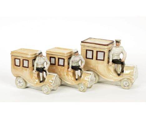Three ceramic bon-bon jars in the form of Edwardian motorcars, believed French,each painted and glazed, in the form of an Edw