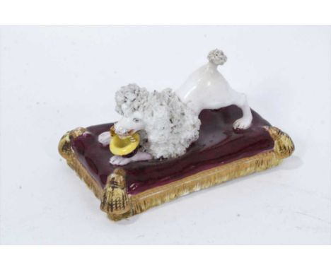 A Minton model of a begging poodle, circa 1840, on a purple cushion base, 10.5cm acrossSome light hairlines and some minor re