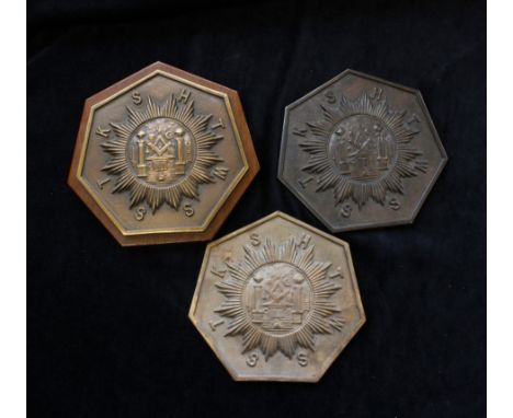 Three masonic wall plaques one mounted on wood depicting the square and compass in central medallion encircled by HTWSSTK (Hi