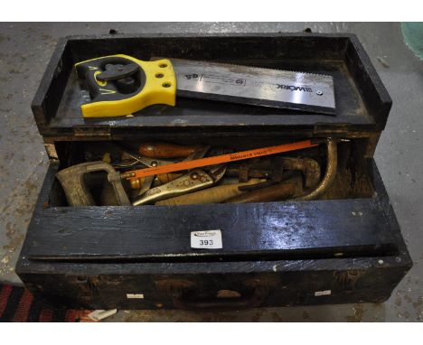 Substantial old wooden tool box containing a saw, a hacksaw, adjustable wrench, part socket set, pliers, spanners, small hack