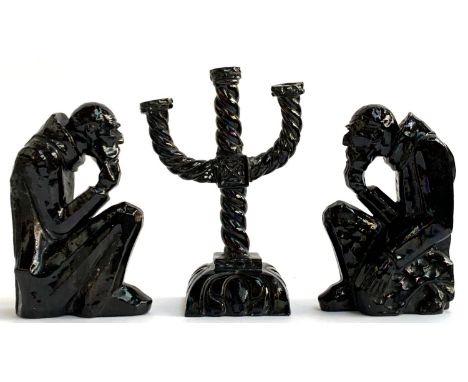 A black lustre glazed three arm candlestick holder, 29cmH, together with 2 matching figures in the form of kneeling men in th