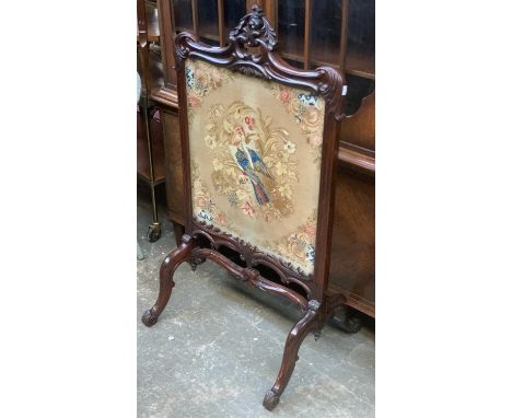 A Victorian carved rosewood firescreen, pierced foliate cresting and acanthus detail, with glazed grospoint embroidery of a f